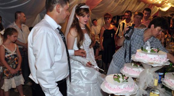Az ifjú pár felvágja a menyasszonyi tortát